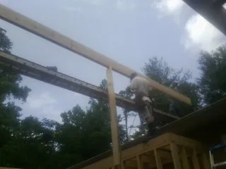 Carpenter setting a ridge beam over a new addition frame — Ice Dam Removal by Roofing Brothers in Bondurant