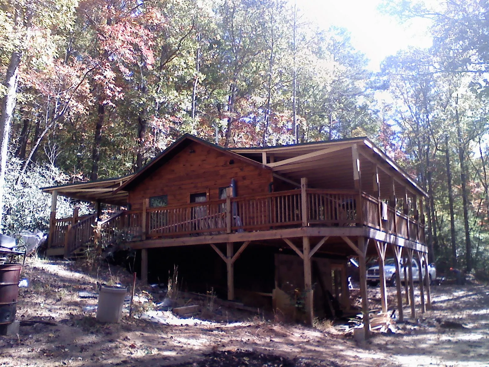 Log cabin with a wraparound porch and metal roof in the fall in Bondurant
