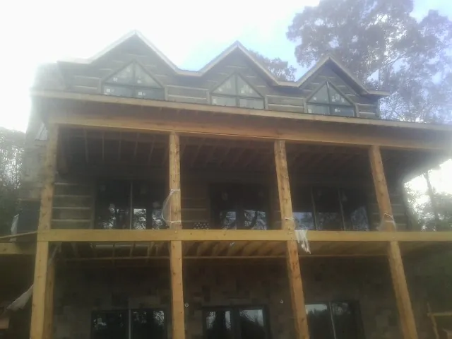 Dormers and porch framing on a large log home under construction — Roof Coating work by our crew in Bondurant