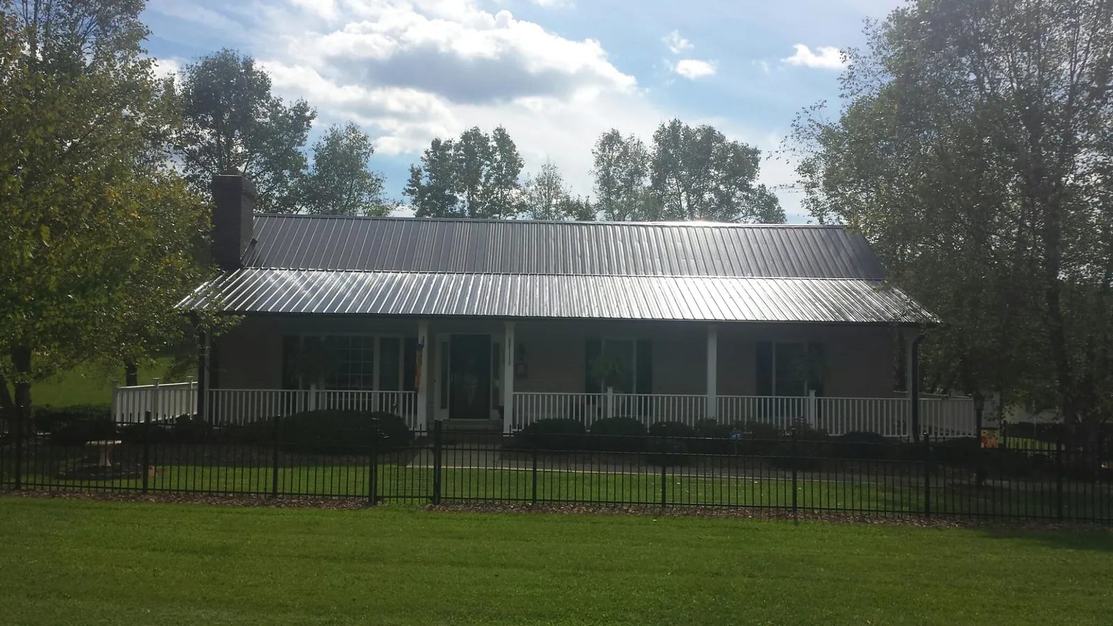 Gray metal roof on a brick ranch with a full width front porch — Gutter Guard Installation work by our crew in Bondurant