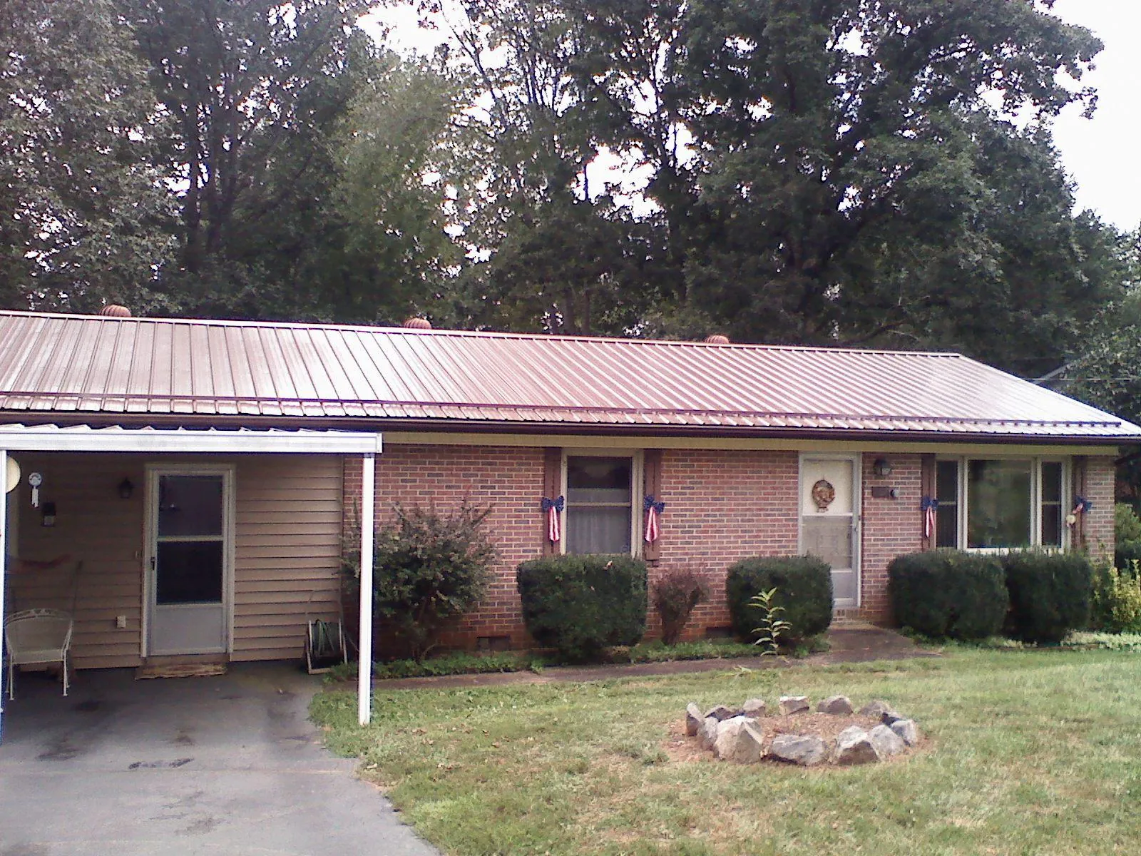 Bronze metal roof and carport on a brick ranch home — Roof Repair work by our crew in Bondurant